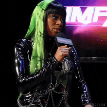 a woman with green hair is speaking into a microphone in front of a sign that says imf