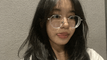 a young woman wearing glasses looks at the camera