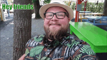 a man wearing glasses and a hat is smiling with the words hey friends behind him