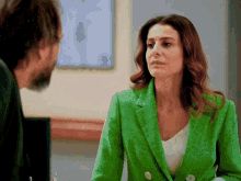 a woman in a green jacket is looking at a man
