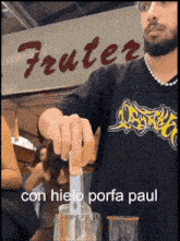 a man in a black shirt is making a drink in front of a sign that says fruter con hielo porfa paul