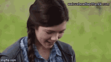 a girl with a braided hair is smiling and looking down .