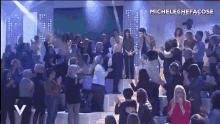 a group of people are dancing on a stage with the name michelechefacose on the bottom right
