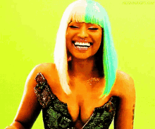 a woman with a green and blonde wig is smiling with the website nicki minaj gifs.com in the corner