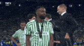 a man wearing a green and white striped shirt that says gree