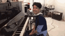 a young man is sitting at a piano in a room .