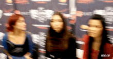 three women are standing next to each other in front of a wall with the words rbd.gif on it .