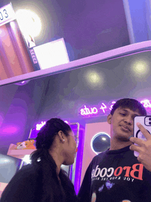 a man taking a selfie with a girl wearing a black shirt that says blooo01