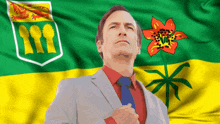 a man in a suit and tie is standing in front of a green and yellow flag with a flower on it