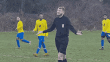 a group of soccer players wearing yellow and blue uniforms are walking on a field
