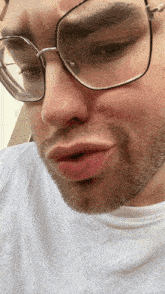 a man wearing glasses and a white shirt is making a face