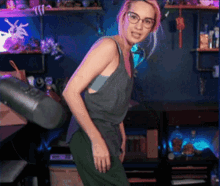a woman wearing glasses and a grey tank top is standing in front of a microphone