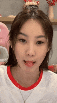 a woman wearing a white shirt with a red collar is sticking her tongue out