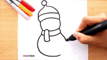 a person is drawing a snowman with a hat and scarf on a piece of paper