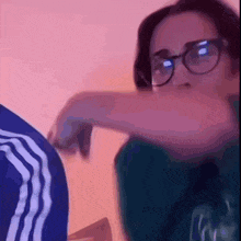 a woman wearing glasses and a blue shirt is sitting in front of a wall .