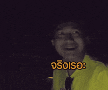 a man in a yellow shirt is making a funny face in a dark room with a foreign language caption