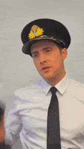 a man in a white shirt and black tie is wearing a black hat