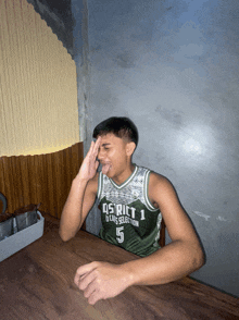 a young man wearing a district 1 jersey sitting at a table