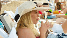 a woman is drinking from a straw while sitting on the beach .