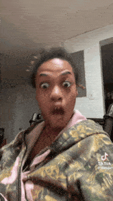 a woman in a camo jacket is making a funny face while sitting in a chair .