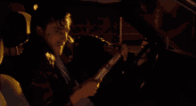 a man is smoking a cigarette while sitting in the driver 's seat of a car