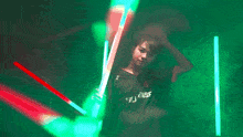 a man in a black shirt that says ' jesus ' on it holds a light saber