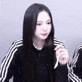 a girl in a black adidas jacket holds a white spoon