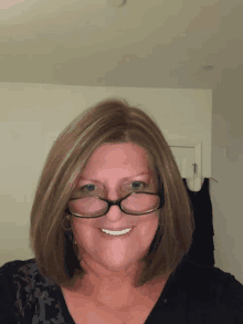 a woman wearing glasses and a black shirt smiles