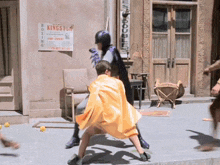 batman and robin are fighting in front of a sign that says kingston