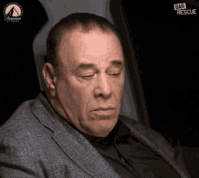 a man in a suit sits in front of a paramount logo