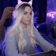 a woman wearing pink cat ears is sitting in front of a computer .