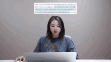 a woman sitting at a desk with a laptop and a foreign language written on the screen