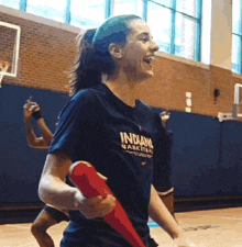 a girl wearing an indiana basketball shirt is holding a red bat