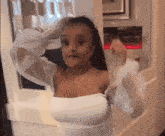 a woman in a white off the shoulder top is standing in front of a glass door