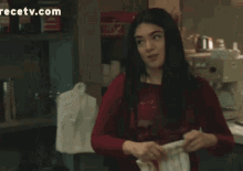 a woman in a red shirt is standing in a kitchen with a recipetv.com logo in the corner