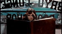 a woman is peeking out from behind a book in a store window .