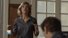 a woman in a blue shirt is talking to a man in a room with the number 10 on the bottom right