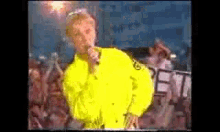 a man in a neon yellow jacket sings into a microphone