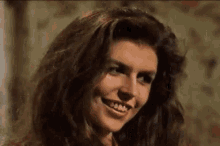 a close up of a woman 's face with long hair smiling .
