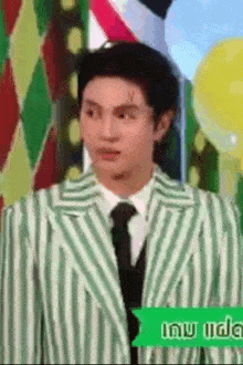a man in a green and white striped suit and tie is making a funny face .