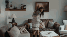 a woman in a sweater is standing next to a couch in a living room