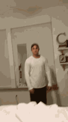 a man in a white shirt stands in front of a mirror