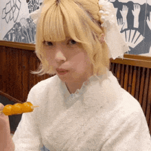 a girl with blonde hair and a white headband is holding a skewer in her hand