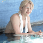 a shirtless man with a towel around his neck is smiling