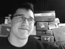 a man wearing glasses is smiling in front of a pile of books