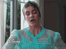a woman is wearing a blue sweater and a headband and is on disney channel .
