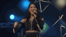 a woman singing into a microphone with a blue light behind her