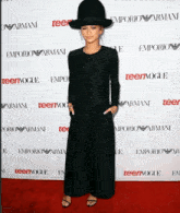a woman wearing a black hat is standing on a red carpet that says teenvogue on it