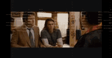 a man in a suit and tie talks to another man with a red circle with the number 2 on it