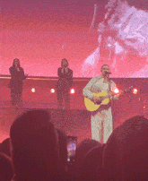 a man singing into a microphone while playing a guitar on stage